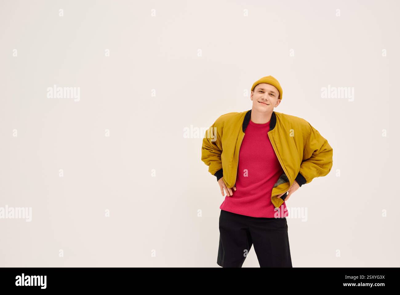 A handsome young man confidently poses in a fashionable outfit ...