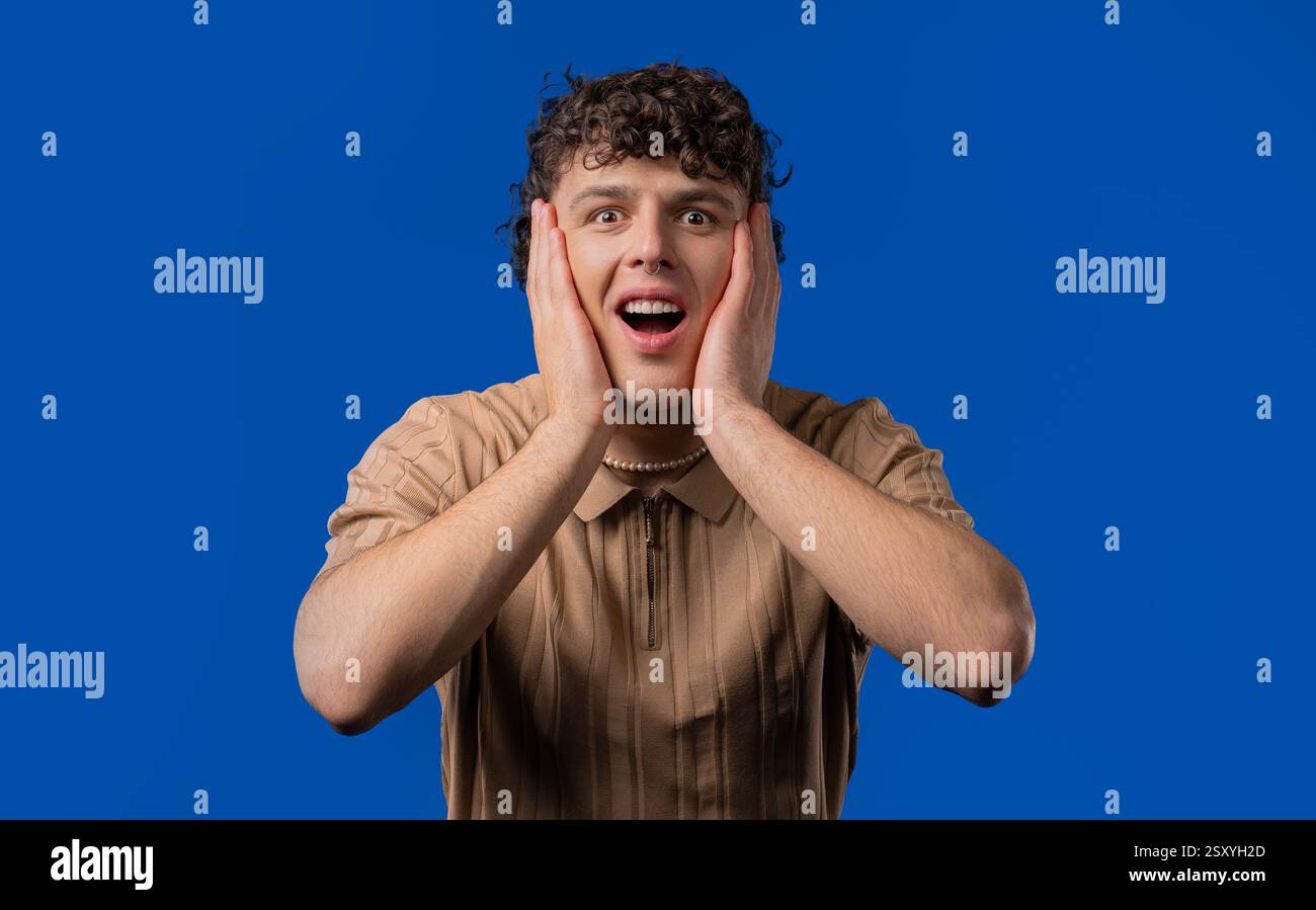 Shocked curly haired man glad, screaming WOW. Impressed guy, unbelievable Stock Photo