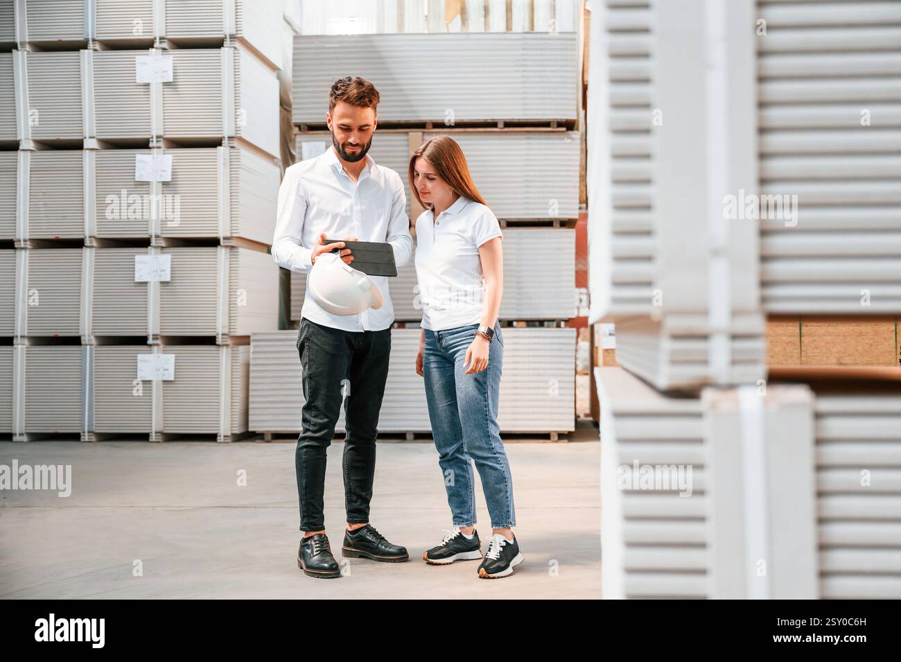 Young manager in formal clothes is working with woman in the warehouse. Stock Photo
