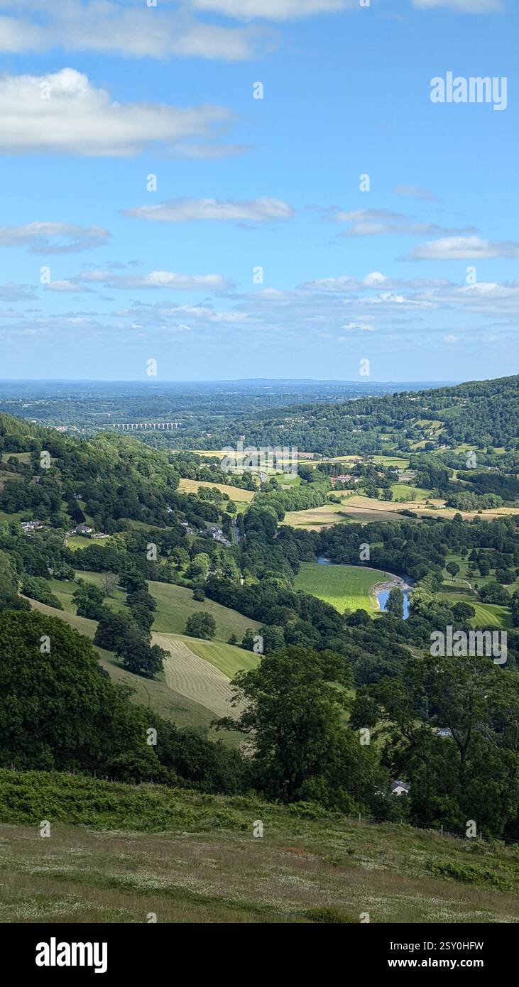 Expansive green valley with rolling hills, vibrant greenery, and a winding river under a bright blue sky. Ideal for nature, landscape, and travel - Smartphone Captured Stock Image