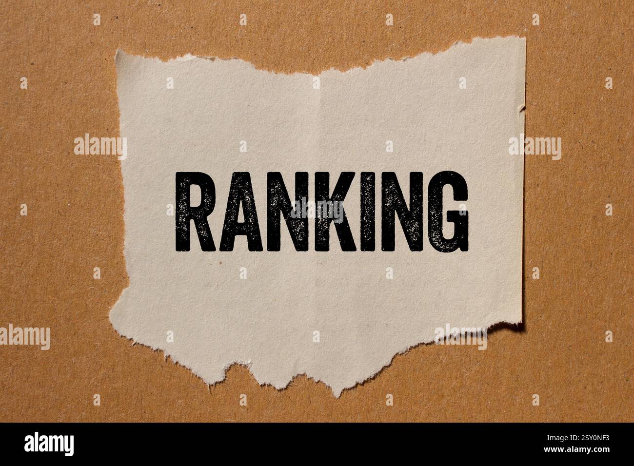 Ranking message written on ripped torn paper piece on brown background ...