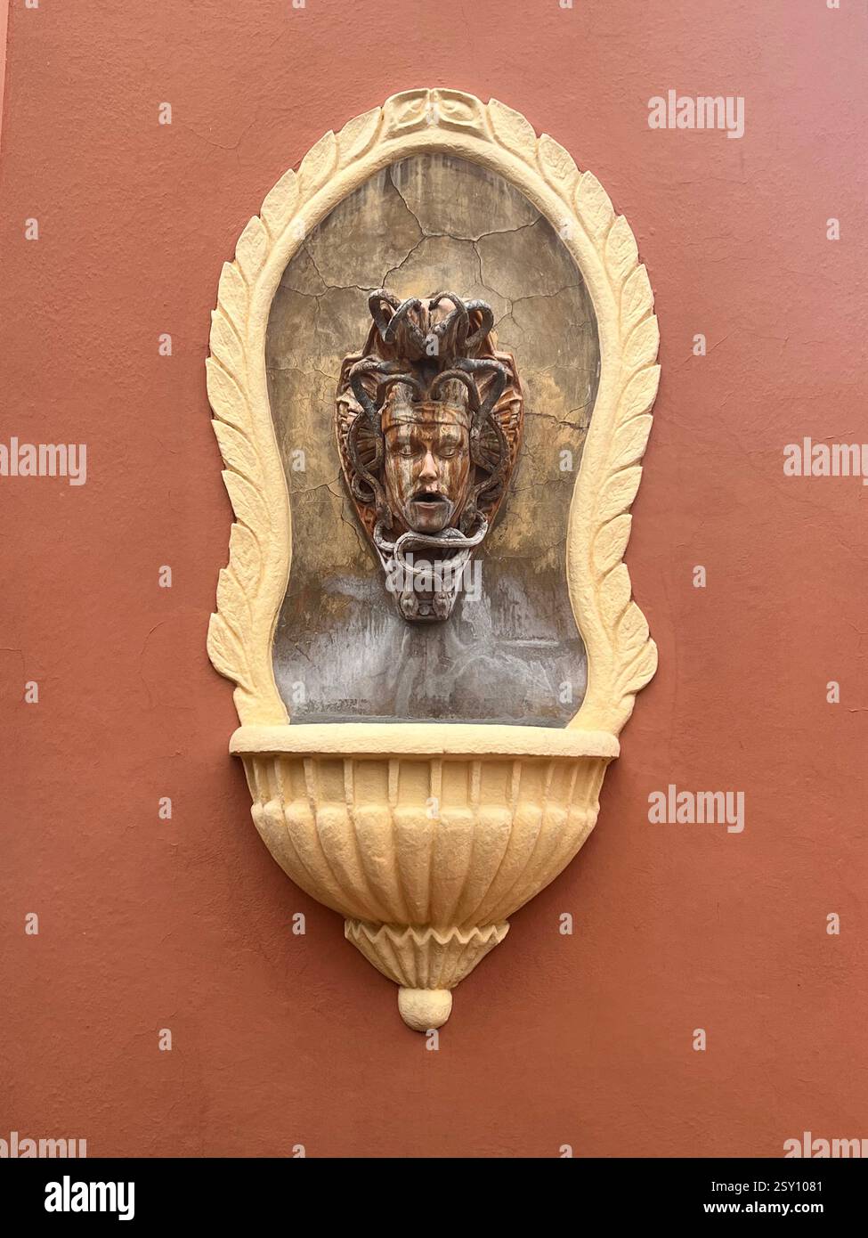 Medusa Wall Fountain on Textured Terracotta Wall - Smartphone Captured Stock Image