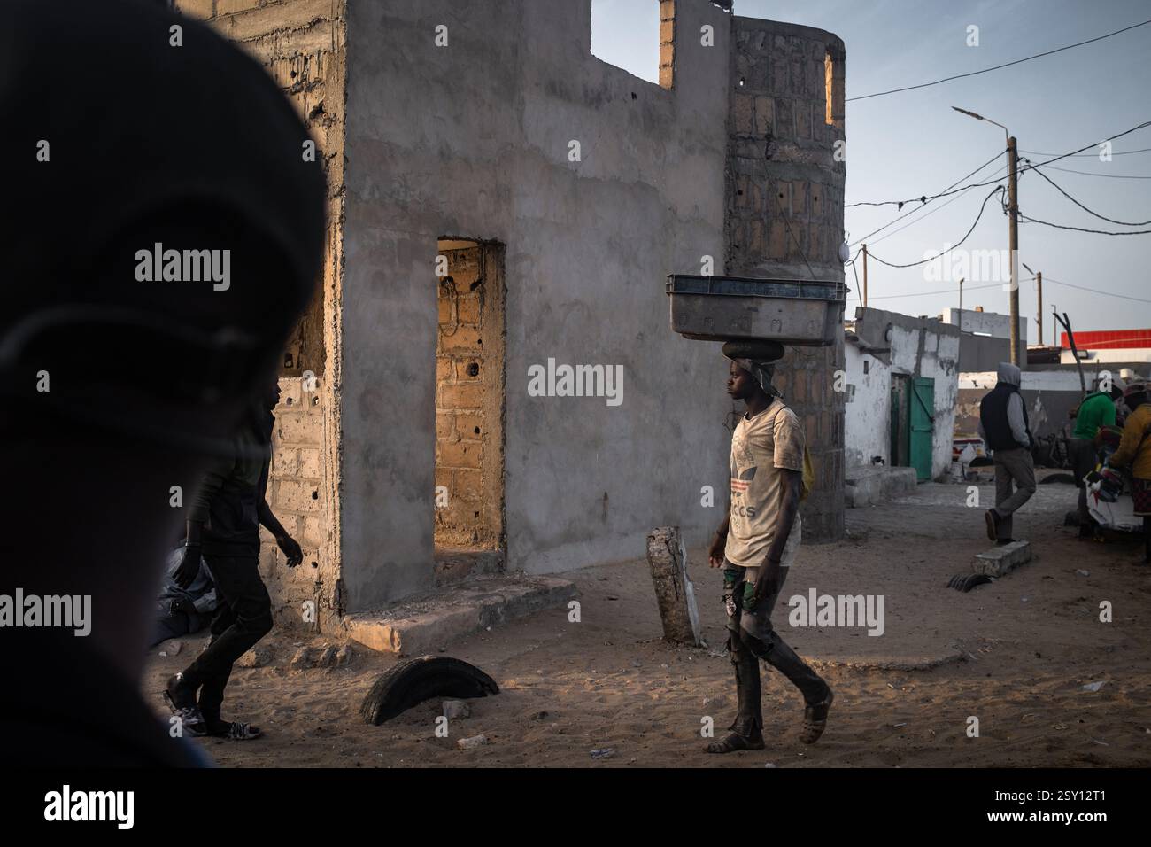 Cayar A man carries a fish crate on his head in an alley in the city center ...