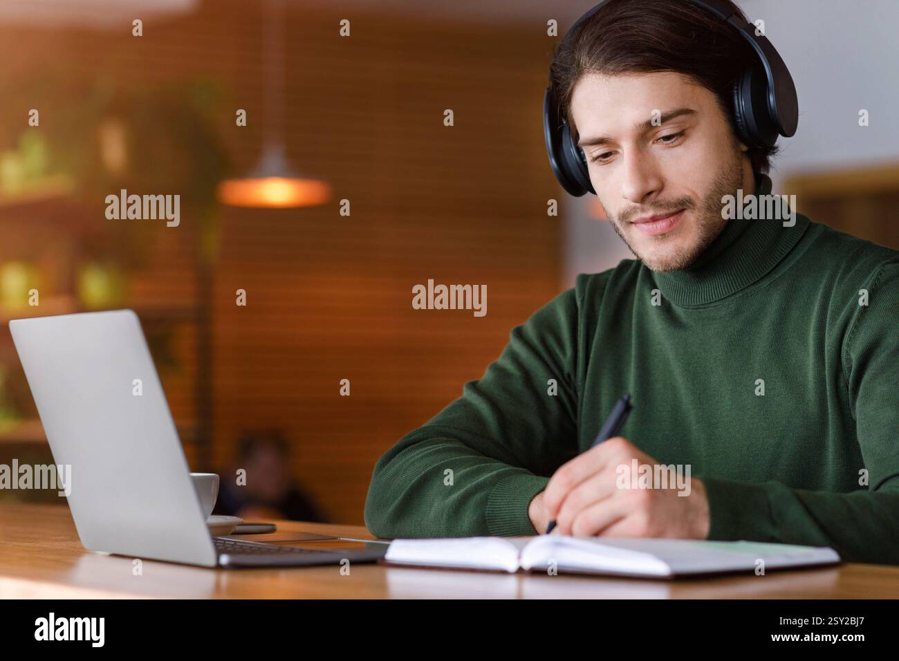 Concentrated guy with headset studying online, using laptop Stock Photo