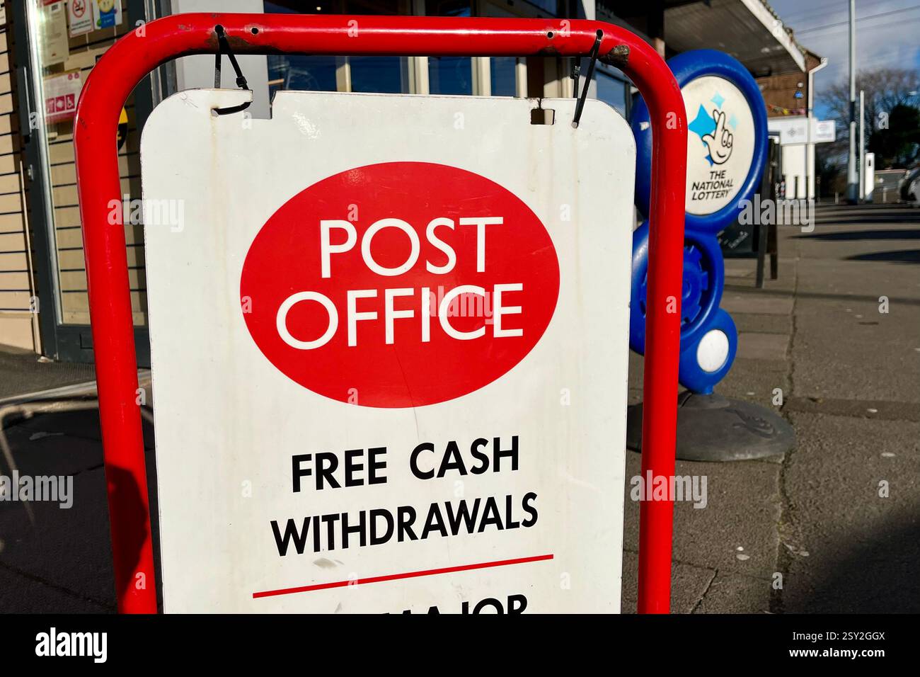 Post Office Outdoor Sign advertising Free Cash Withdrawals, with a National Lottery Sign in the background. Killay, Swansea, Wales, United Kingdom. - Smartphone Captured Stock Image