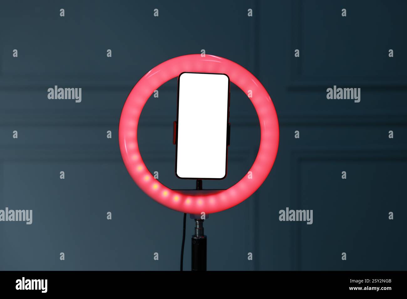 Ring lamp with smartphone against wall indoors Stock Photo