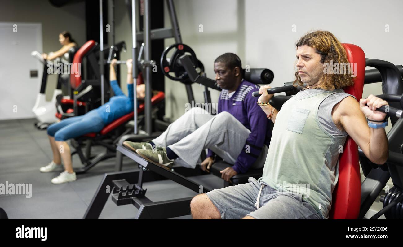 Muscular sports bodybuilder in gym is engaged in simulators Stock Photo ...