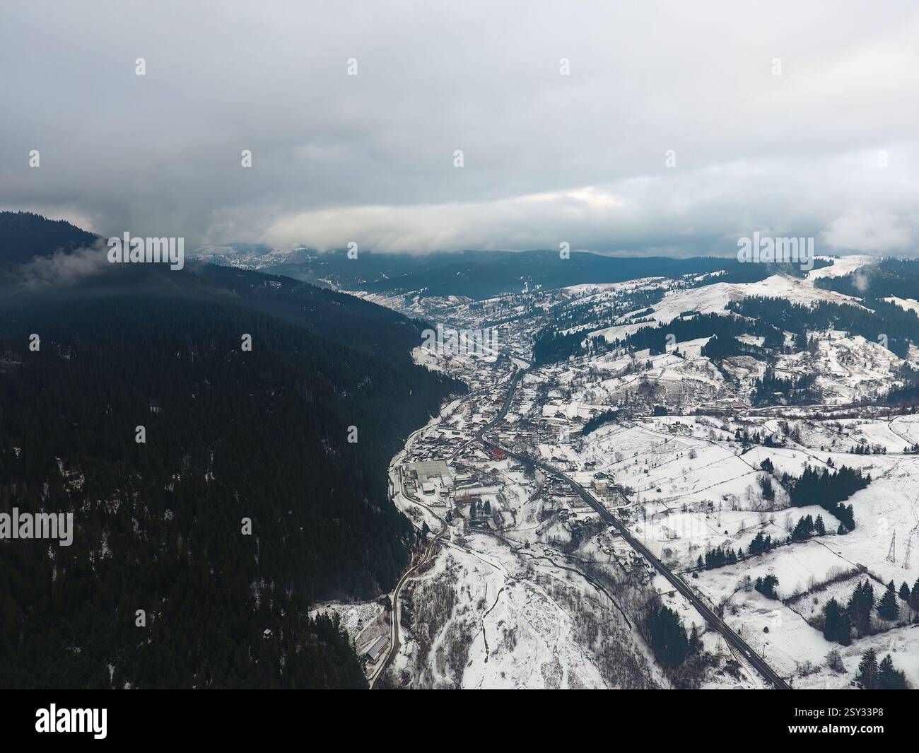 Aerial view of a snow covered valley surrounded by forested hills ...