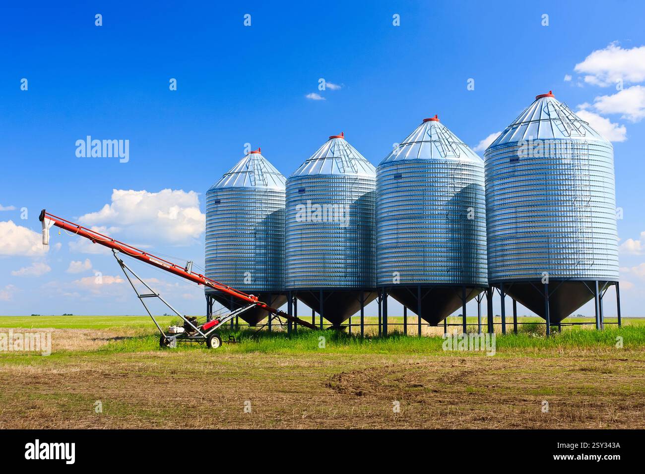 Field of grain silos with a tractor in front of them. The silos are all ...
