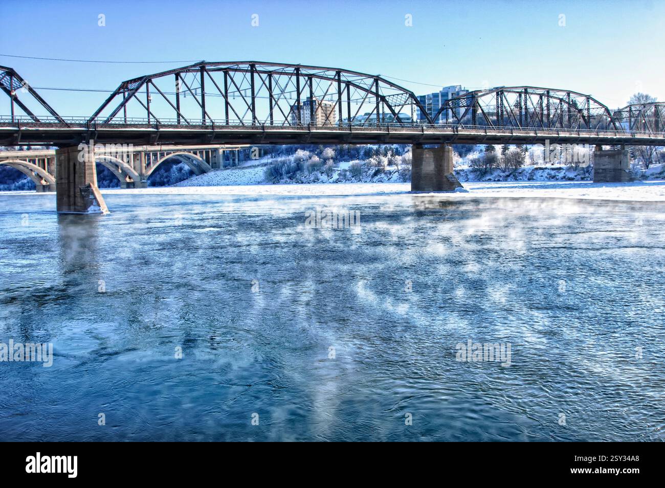 Bridge spans a river with steam rising from the water. The steam is ...