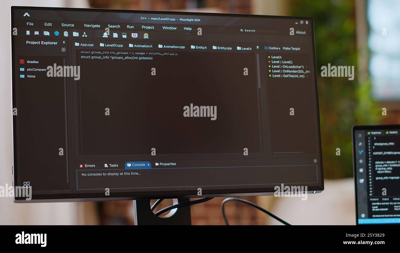 Asian programmer seen typing code for a user interface design on dual monitors, working in a digital workspace. Woman coder working on software engineering and front end development. Camera B. Stock Photo