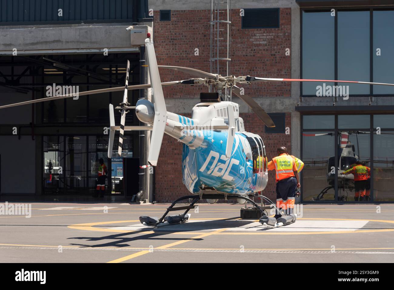 Cape Town South Africa. 25.12. 2024. Flight line controllers on duty alongside a passenger carrying helicopter used on scenic tours around the city Stock Photo