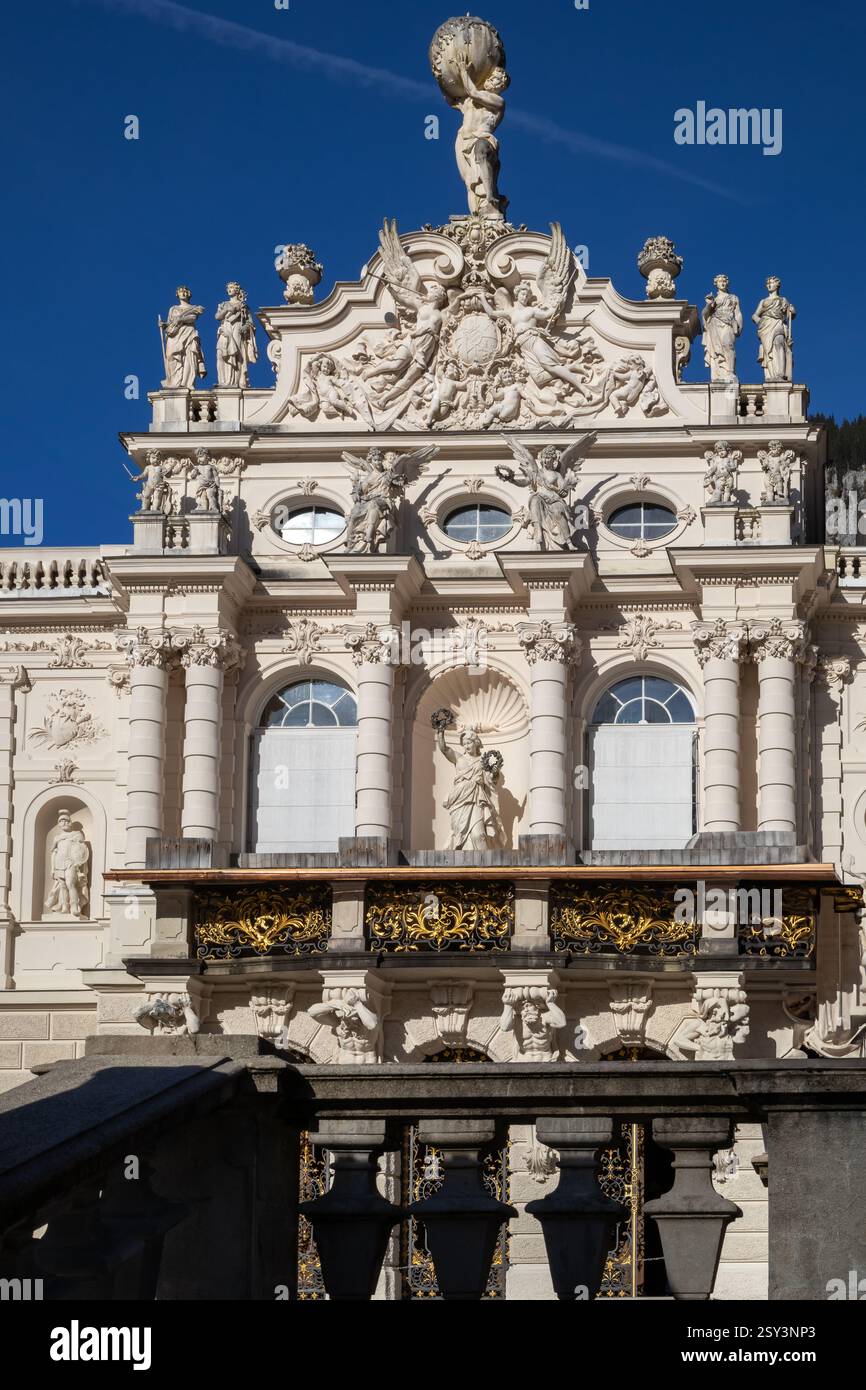 A low-angle, eye-level shot of the Linderhof Palace rooftop, featuring a sculpture of Atlas holding the globe, surrounded by other statues and ornate. Stock Photo