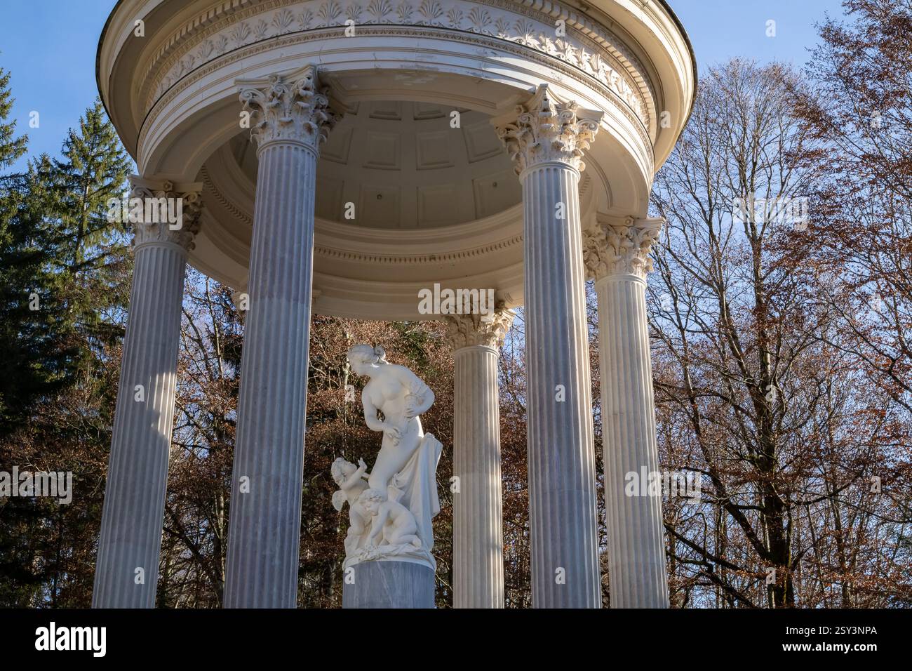 A low-angle, eye-level shot of the Linderhof Palace rooftop, featuring a sculpture of Atlas holding the globe, surrounded by other statues and ornate. Stock Photo