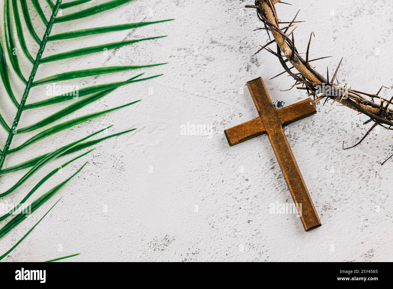 Crown of thorns and wooden cross with palm leaves on a gray background ...