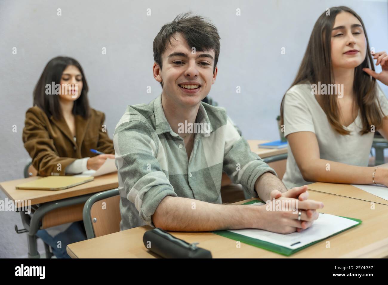 Portrait of a cheerful male student sitting at desk in classroom, attending a lesson at high school, college or university Stock Photo