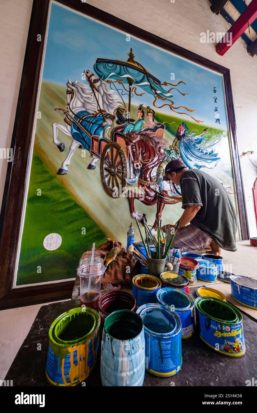 An artist restores a large mural in the Phuoc Kien Assembly Hall in Hoi ...