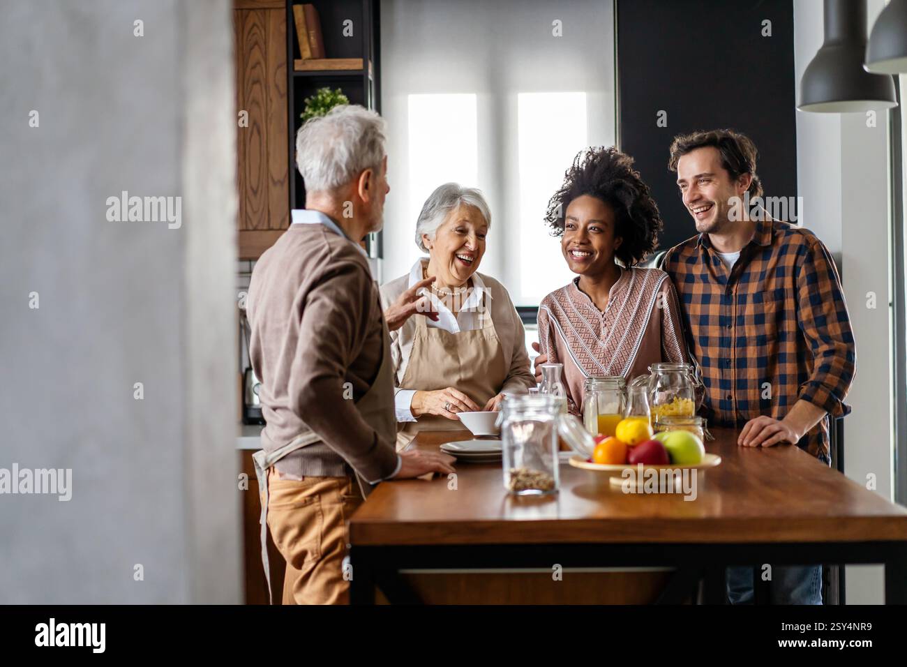 Multi generation multiethnic family having fun, talking around a festive kitchen table. Stock Photo