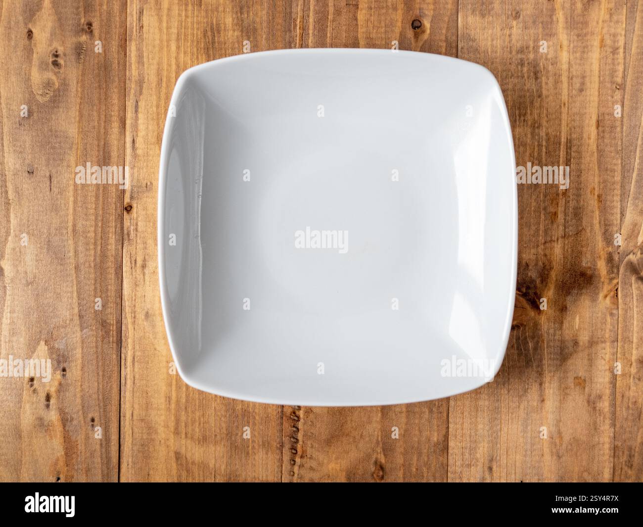 Empty square white plate on wooden background. Top view Stock Photo