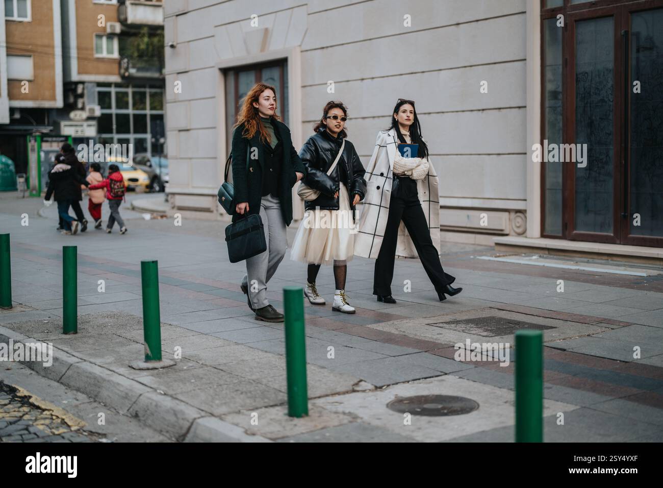 Three businesswomen walking down the street in stylish urban outfits ...