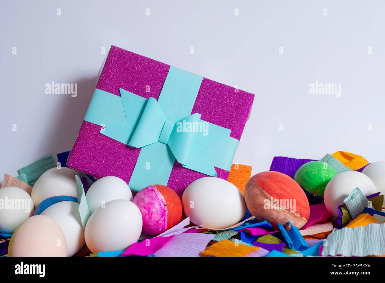 Easter greeting card, colorful Easter eggs with gift box and crepe paper on white background, with copy space. Stock Photo