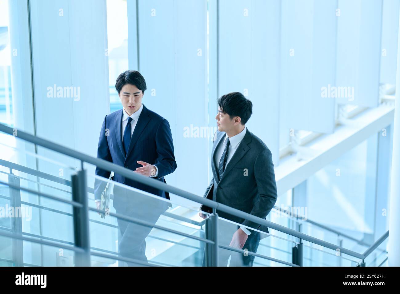 Two Japanese Businessmen Walking Up A Stairwell Stock Photo