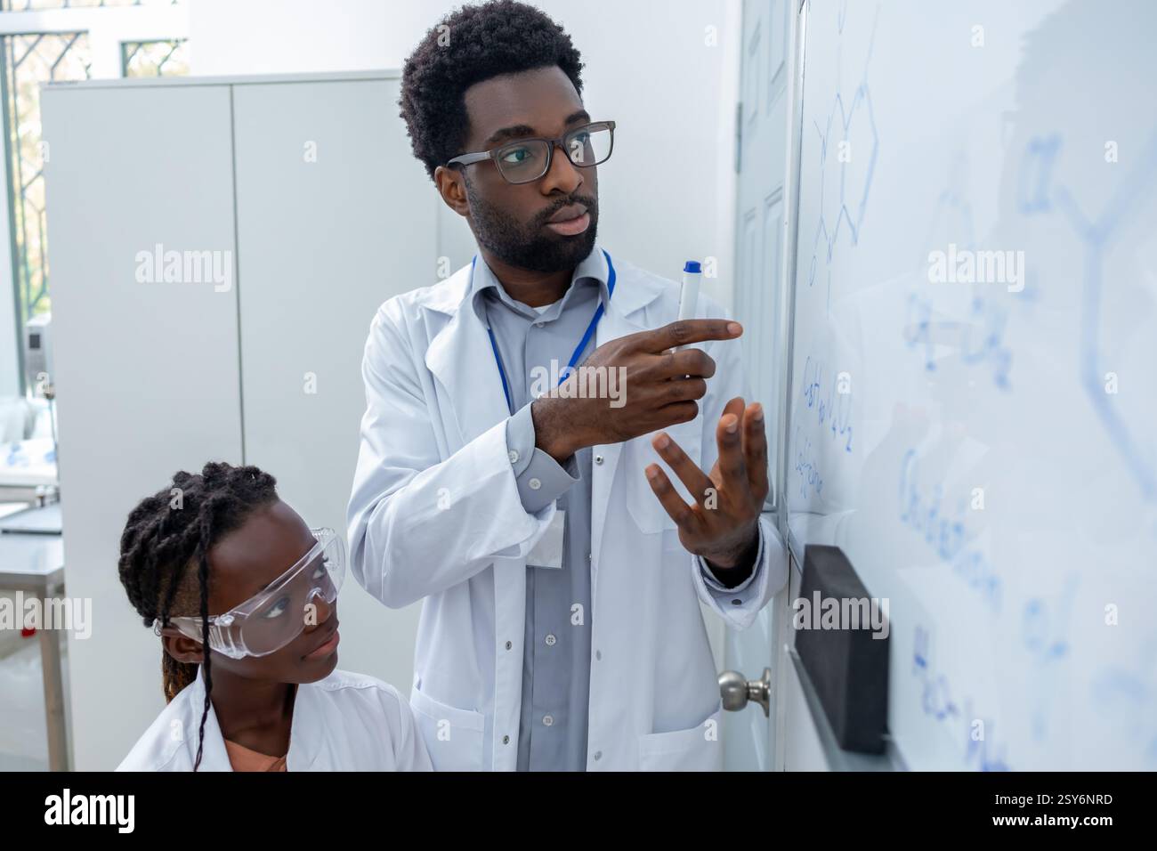 African american man in lab coat standing at the blackboard in a school ...