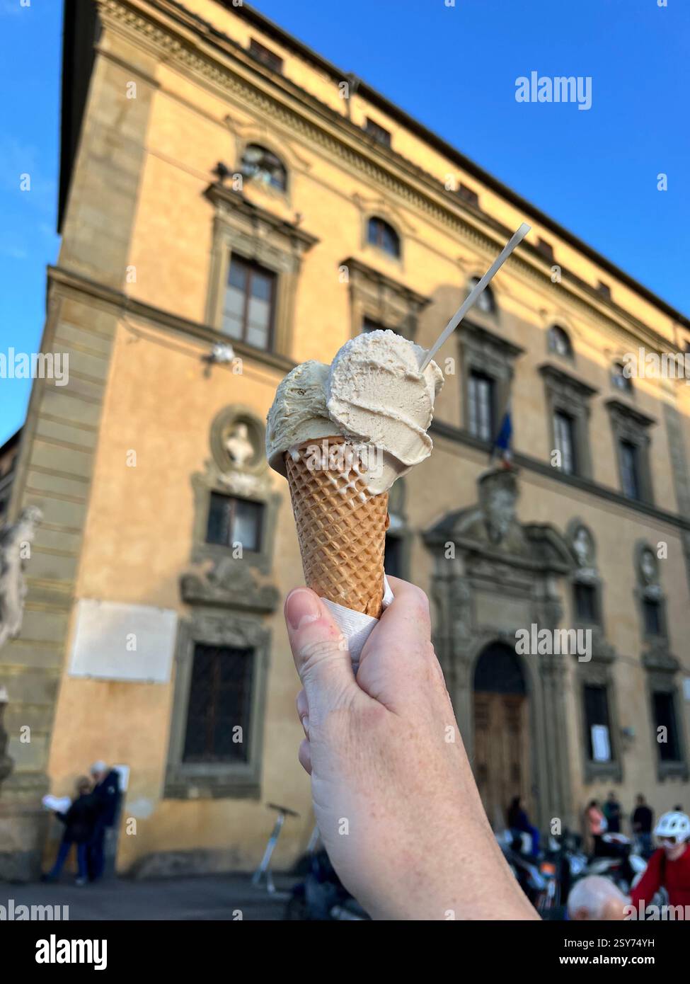 A hand holding a gelato cone against a historic European building - Smartphone Captured Stock Image