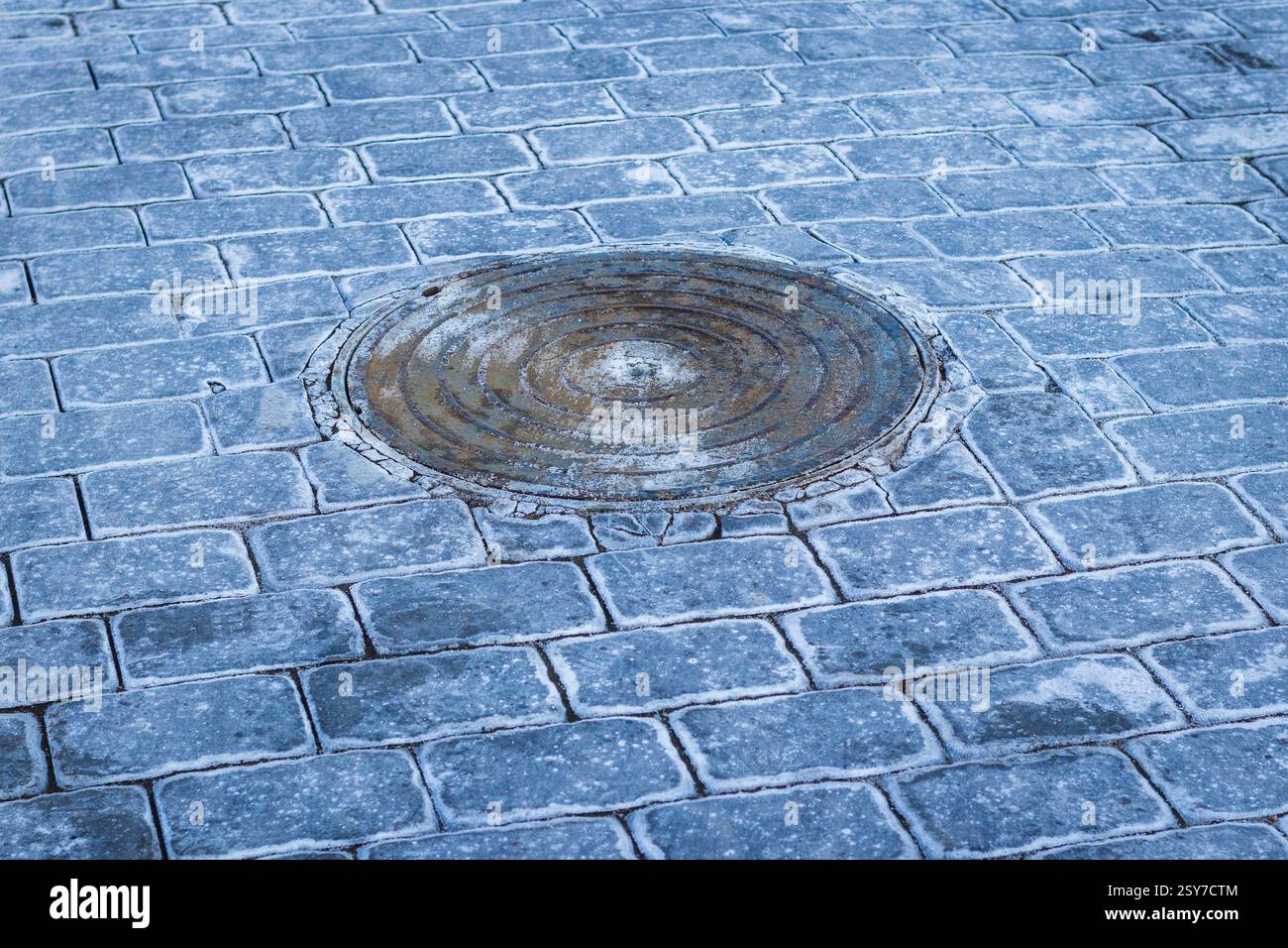 Manhole and interlock bricks with frost on them. Stock Photo