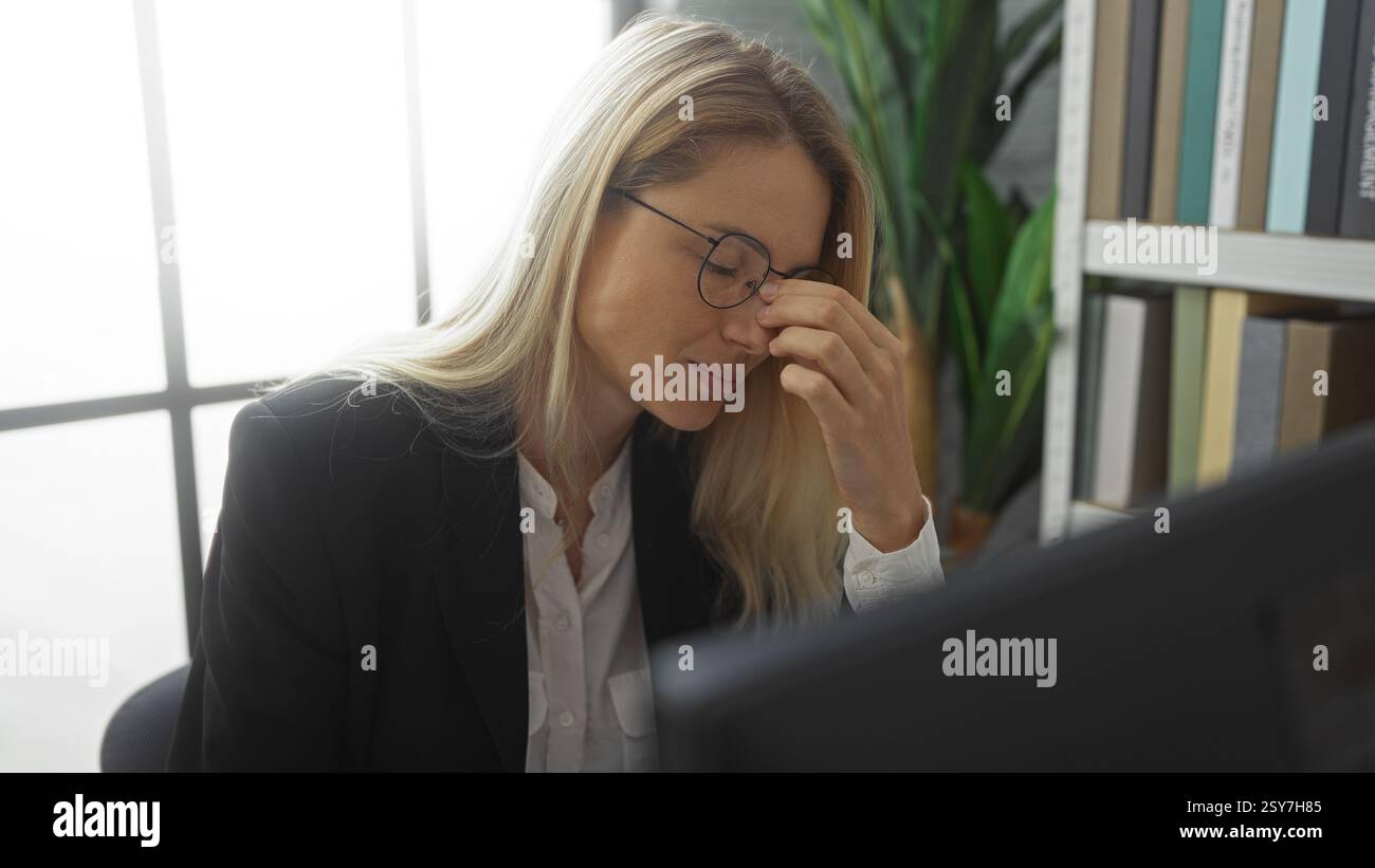 Woman stressed at work rubbing temples in office with glasses and ...