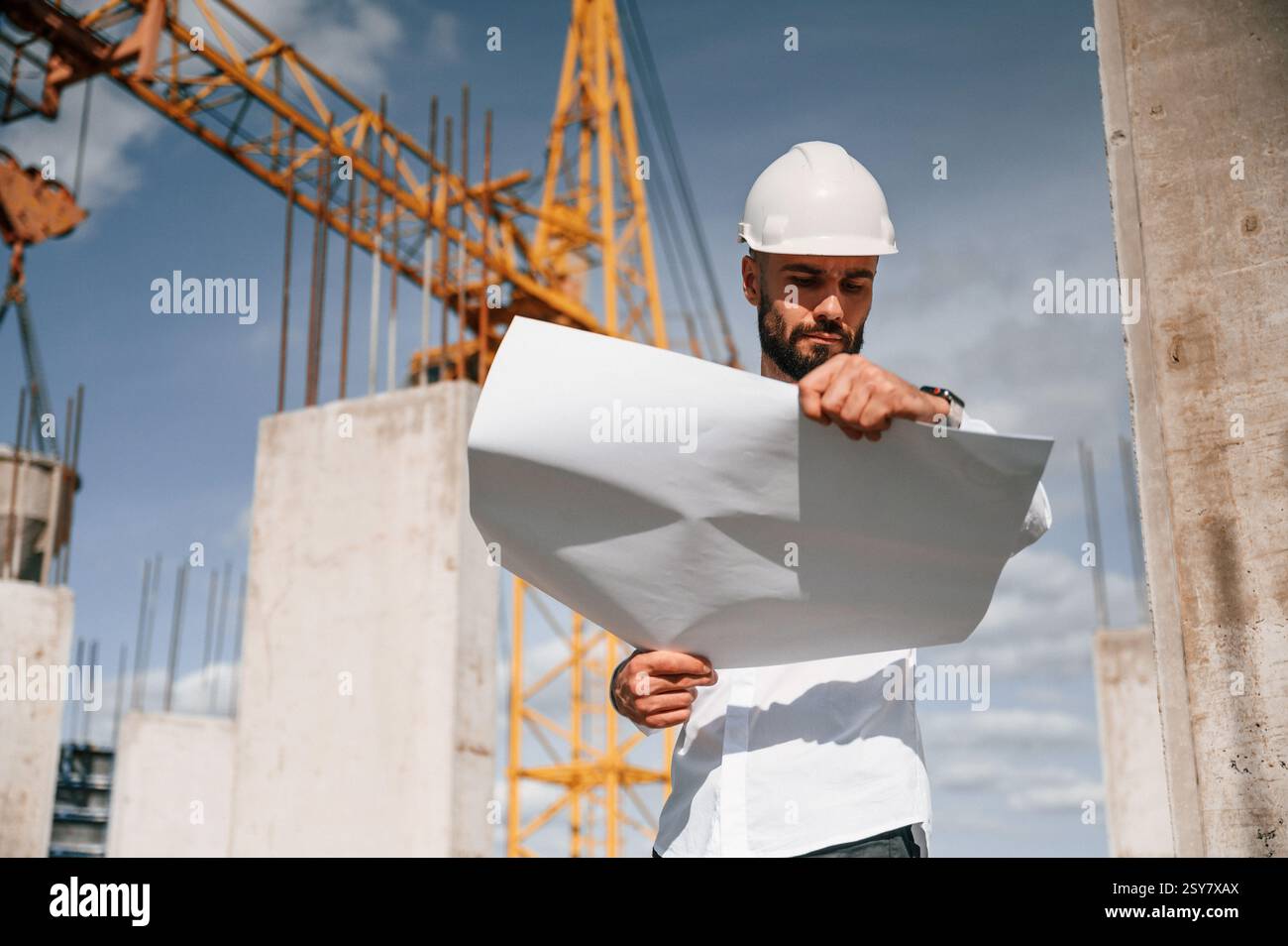 Inspecting a plan. Man in uniform is working on the construction site. Stock Photo