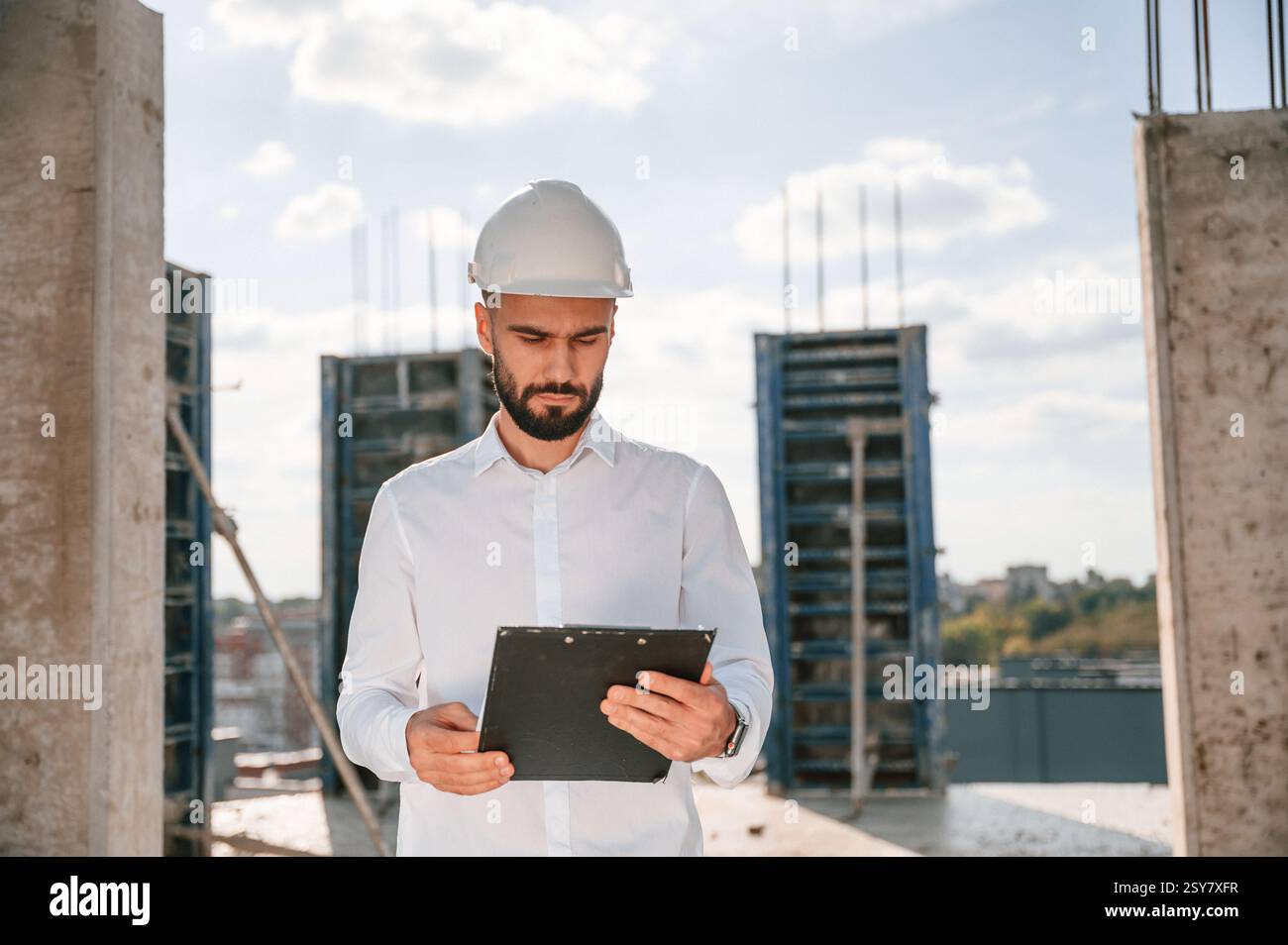 With notepad with documents. Foreman in uniform is working on the construction site. Stock Photo