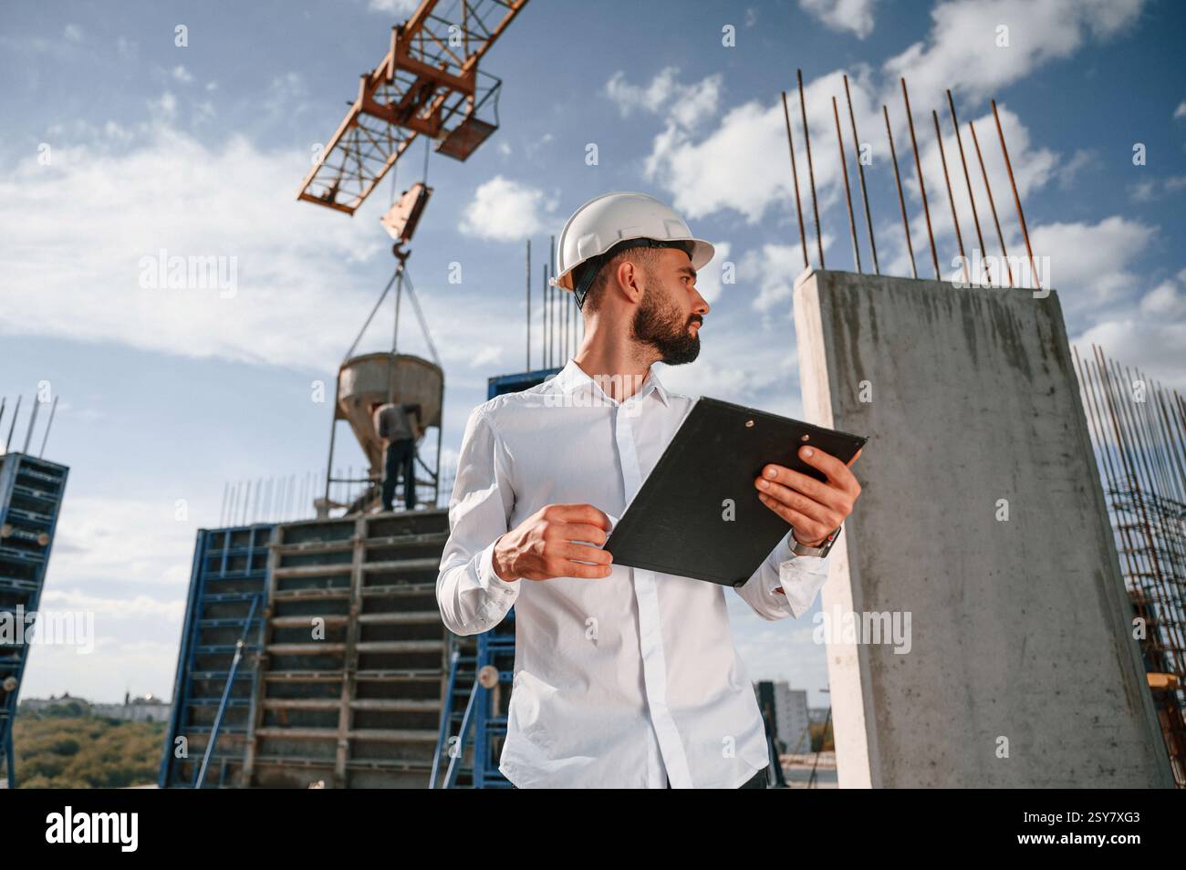 With notepad with documents. Foreman in uniform is working on the construction site. Stock Photo