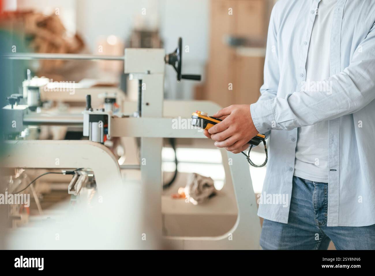 Modern printing machine. Typography worker in white clothes is indoors. Stock Photo