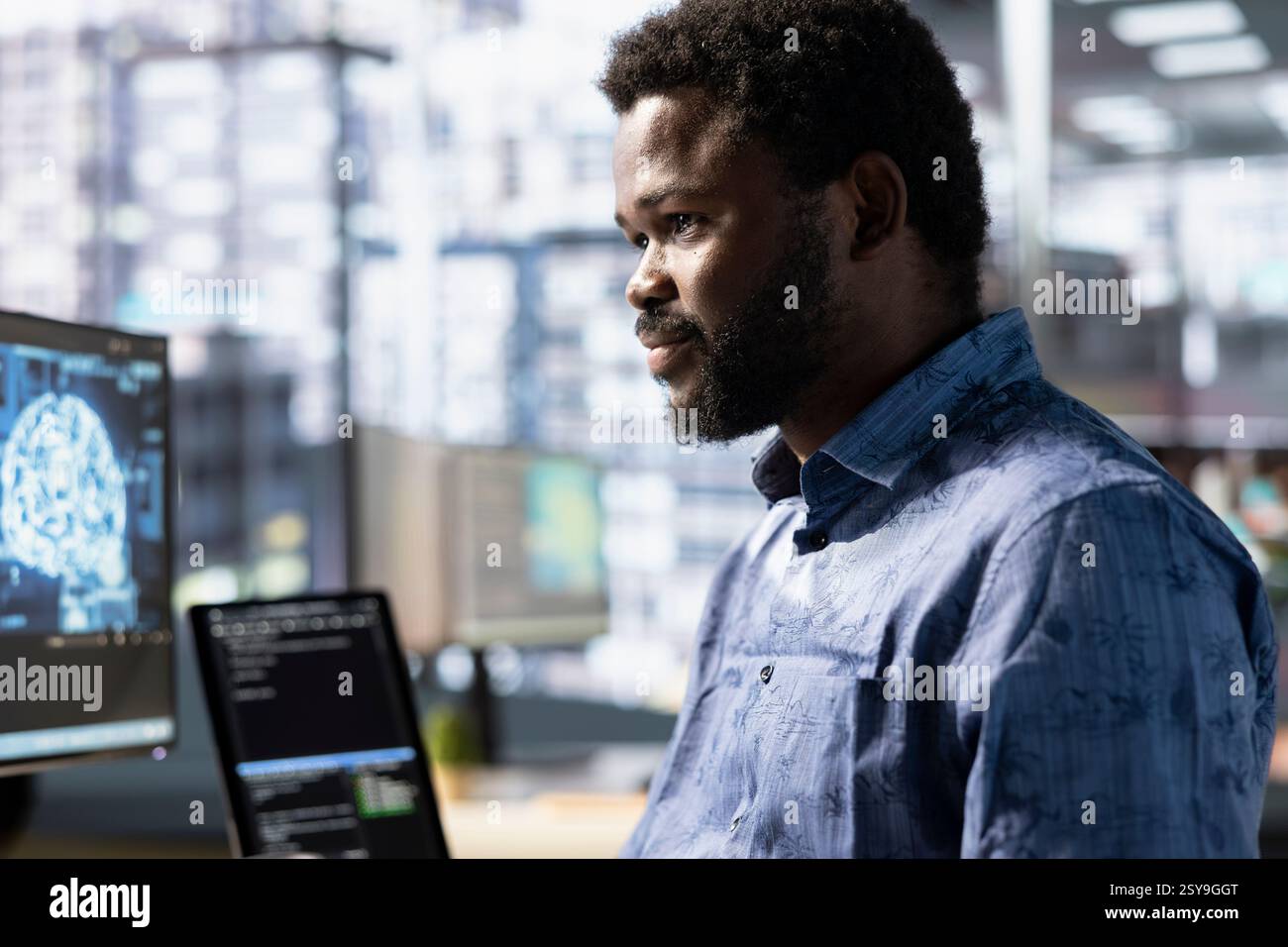 Cheerful employee utilizing AI cloud computing resources and platforms to train and deploy large scale machine learning models. Smiling african amertican man monitoring and maintaining company systems Stock Photo