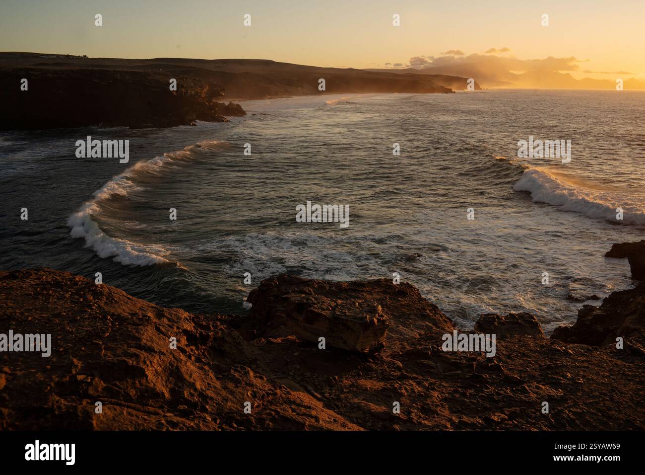 Dramatic view of powerful waves hitting rugged rocks with a sunset ...