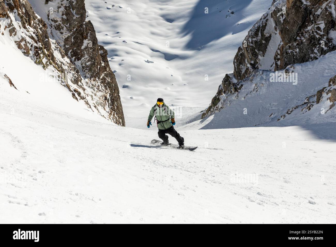 A snowboarder skillfully descends a steep, snowy mountain slope ...