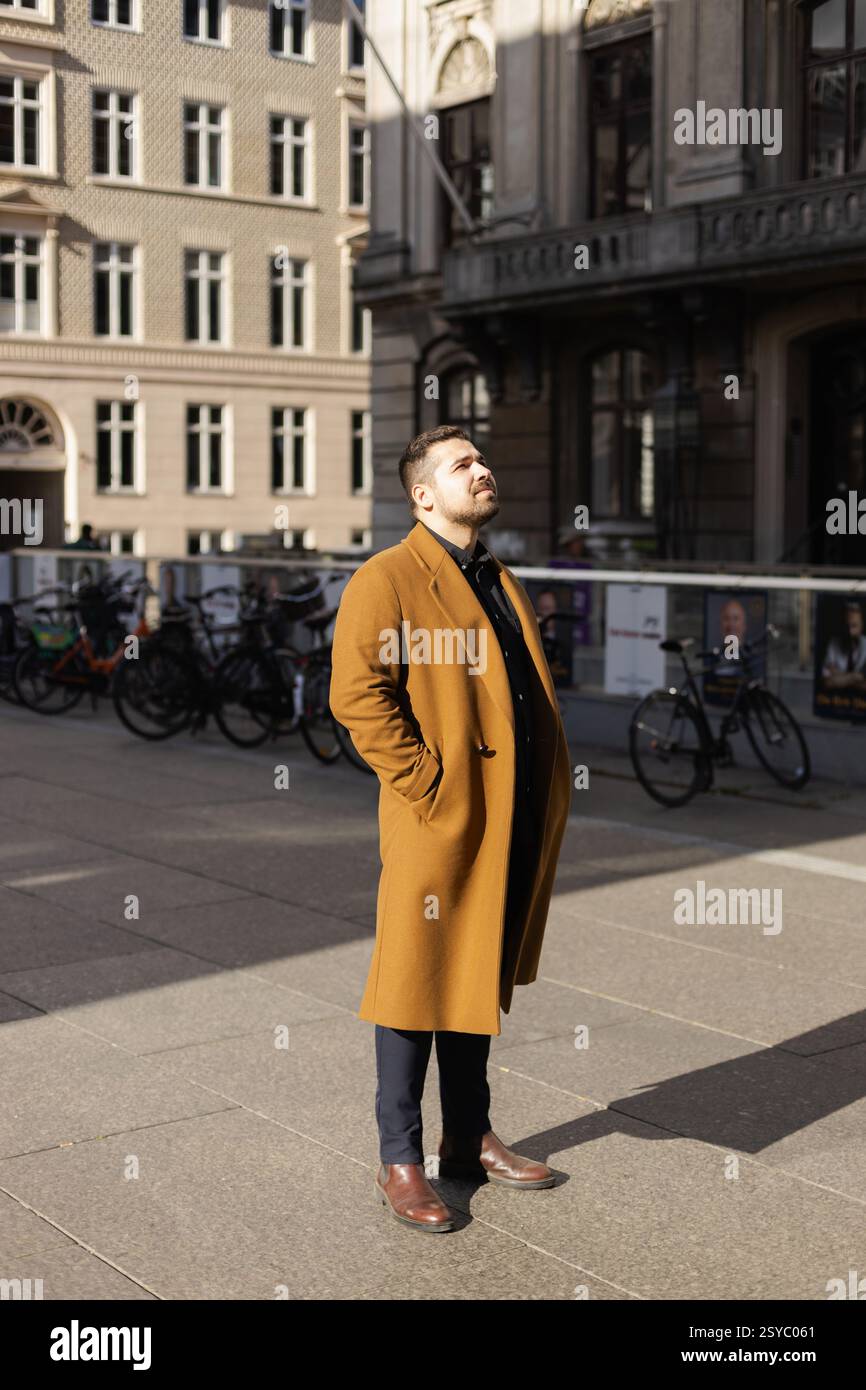 Businessman standing outside in sun ray in European city center Stock Photo