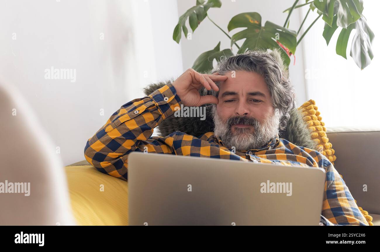Focused mature man working from home on laptop computer Stock Photo
