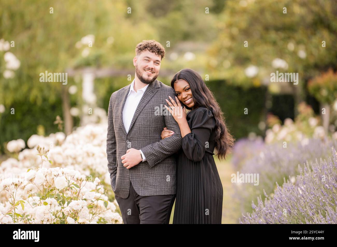 A happy couple celebrating their engagement in a garden Stock Photo
