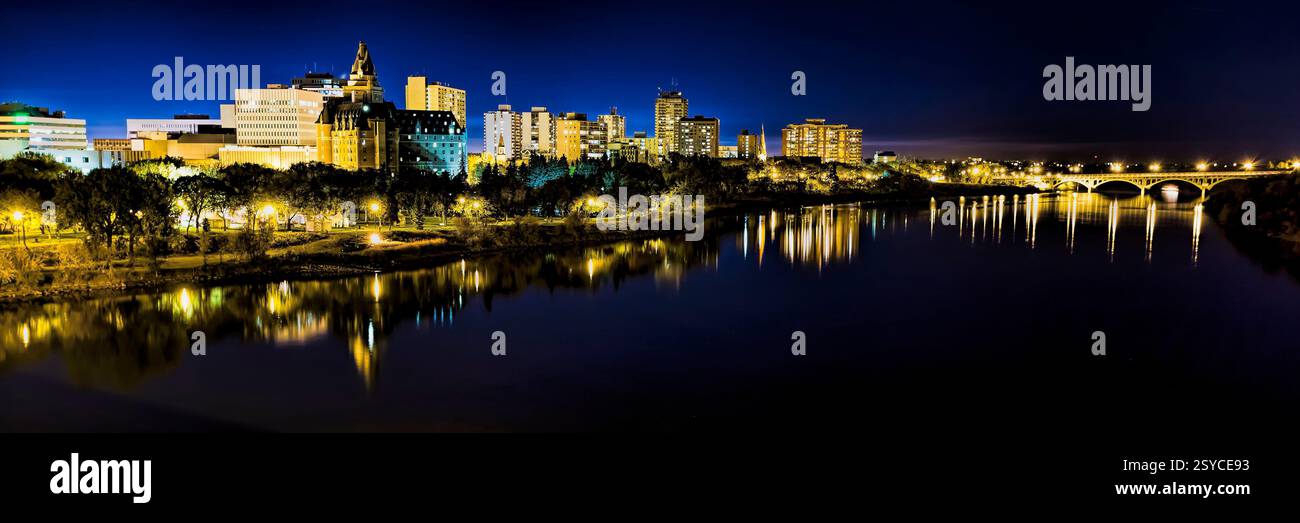 City skyline with a river running through it. The river is lit up at night. There are many lights in the city Stock Photo