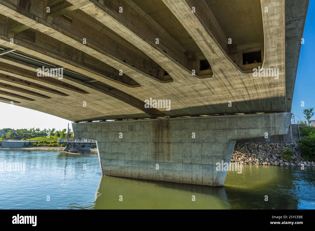 Bridge with a large concrete pillar in the middle. The pillar is surrounded by water. The water is green and calm Stock Photo