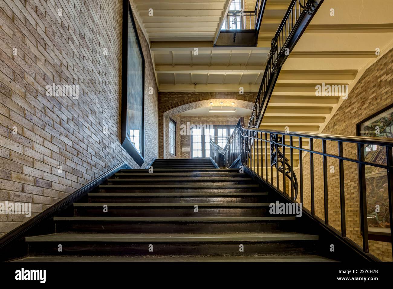 Staircase with a black railing. The stairs are made of brick. There is ...