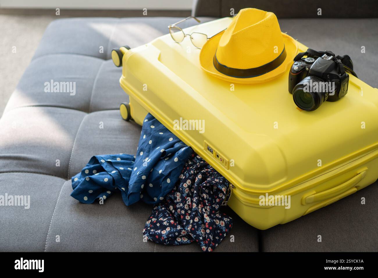 A bright yellow suitcase struggles to stay closed, with clothes ...