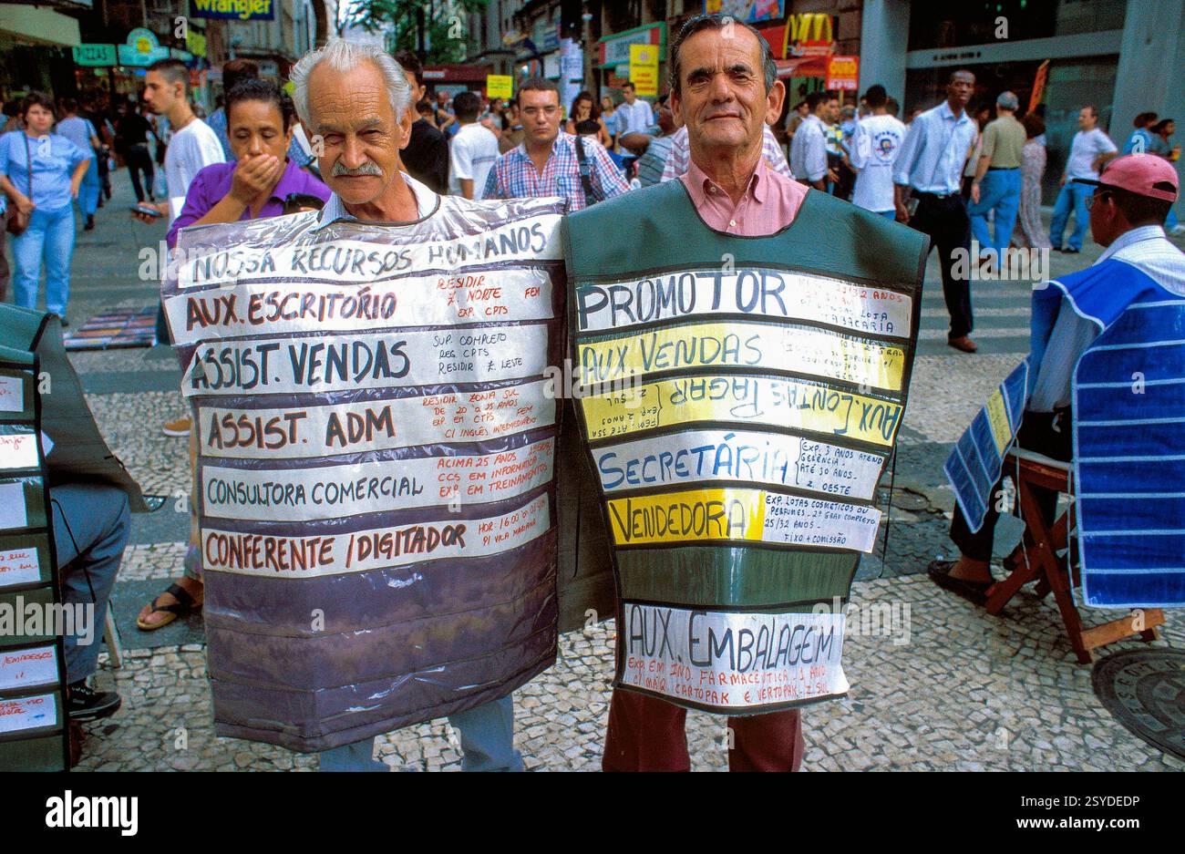 Brazil, Sao Paulo. Older men advertise for an employment agency in a shopping center. Stock Photo