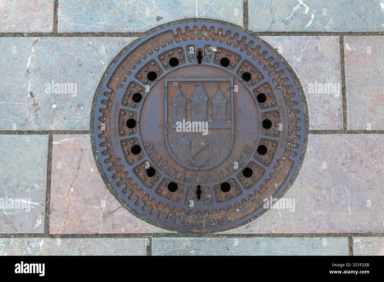 A close-up shot of a round manhole cover embedded in a cobblestone ...