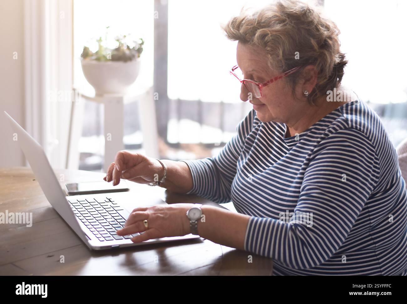 Senior woman sitting at table using laptop computer Stock Photo