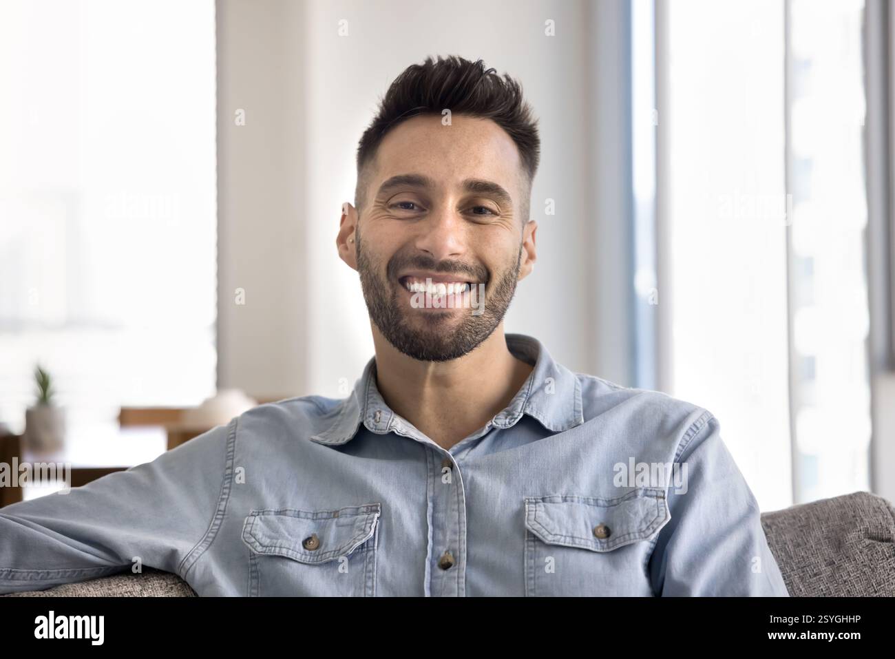 Man looking at camera with joyful expression seated on couch Stock Photo