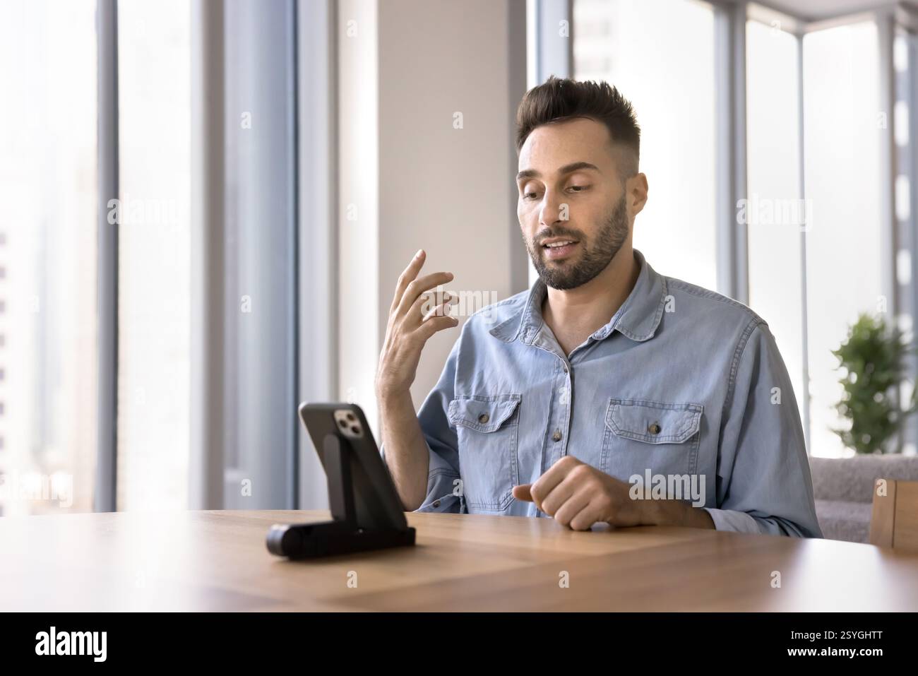 Serious Hispanic man speaking to client through videocall Stock Photo