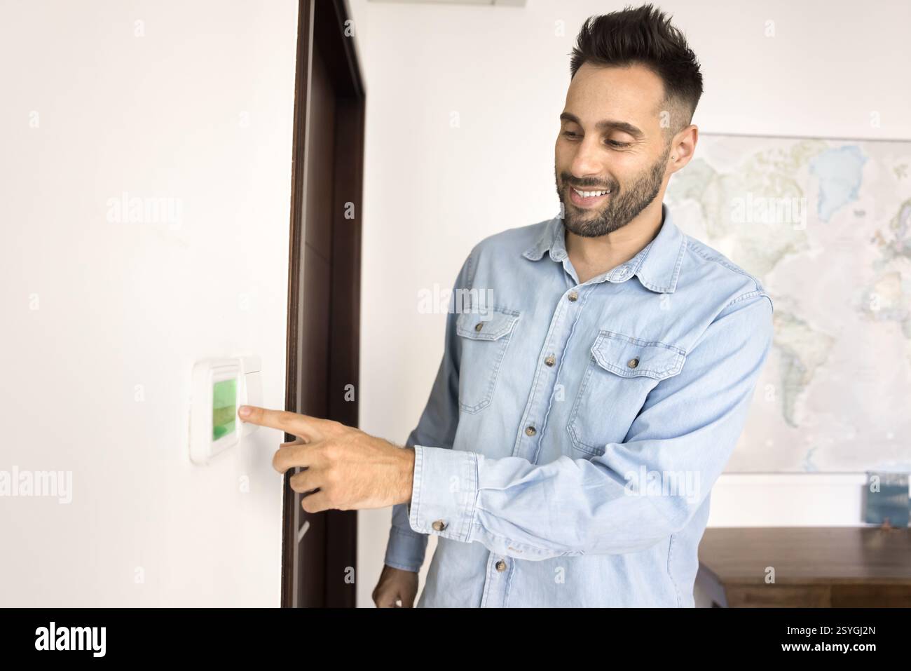 Man adjusts settings, switch on thermostat or smart control panel Stock Photo